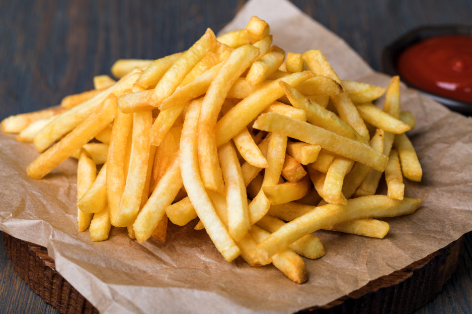 Tasty french fries on cutting board